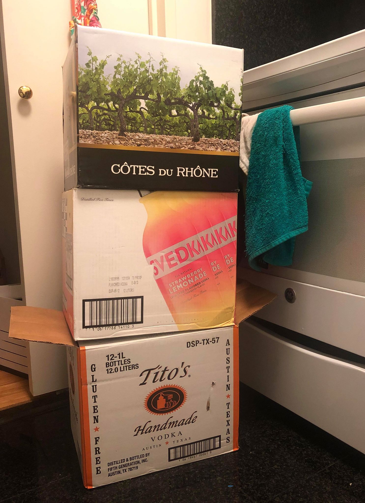 three cardboard liquor boxes stacked near an oven