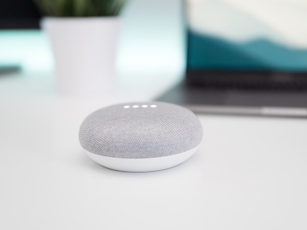 A Google Home Mini on a white table.