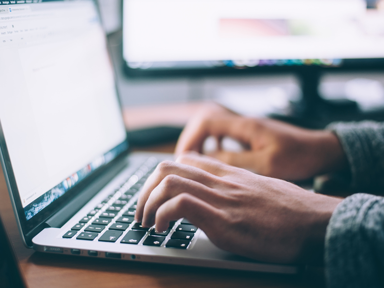 hands typing on laptop keyboard