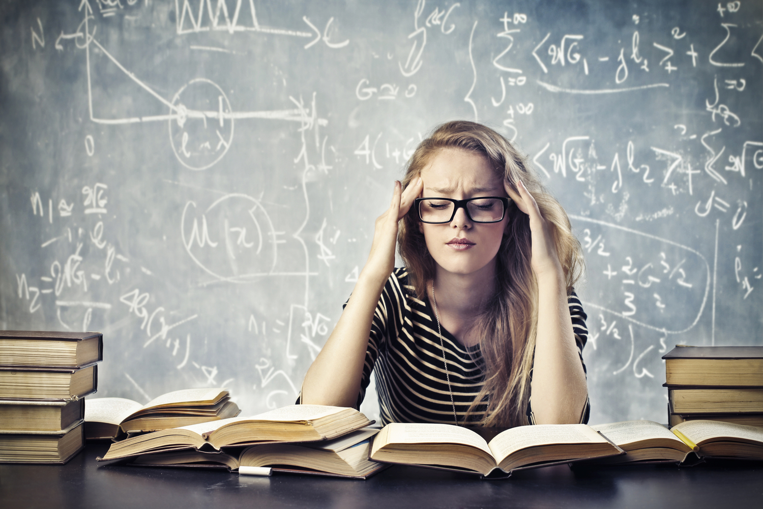 a blonde woman looking stressed out about math and surrounded by books