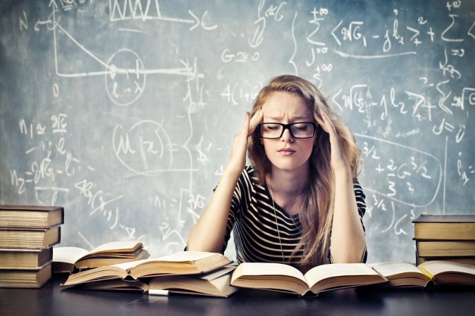 a blonde woman looking stressed out about math and surrounded by books