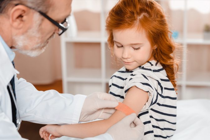 child getting a vaccine by her doctor