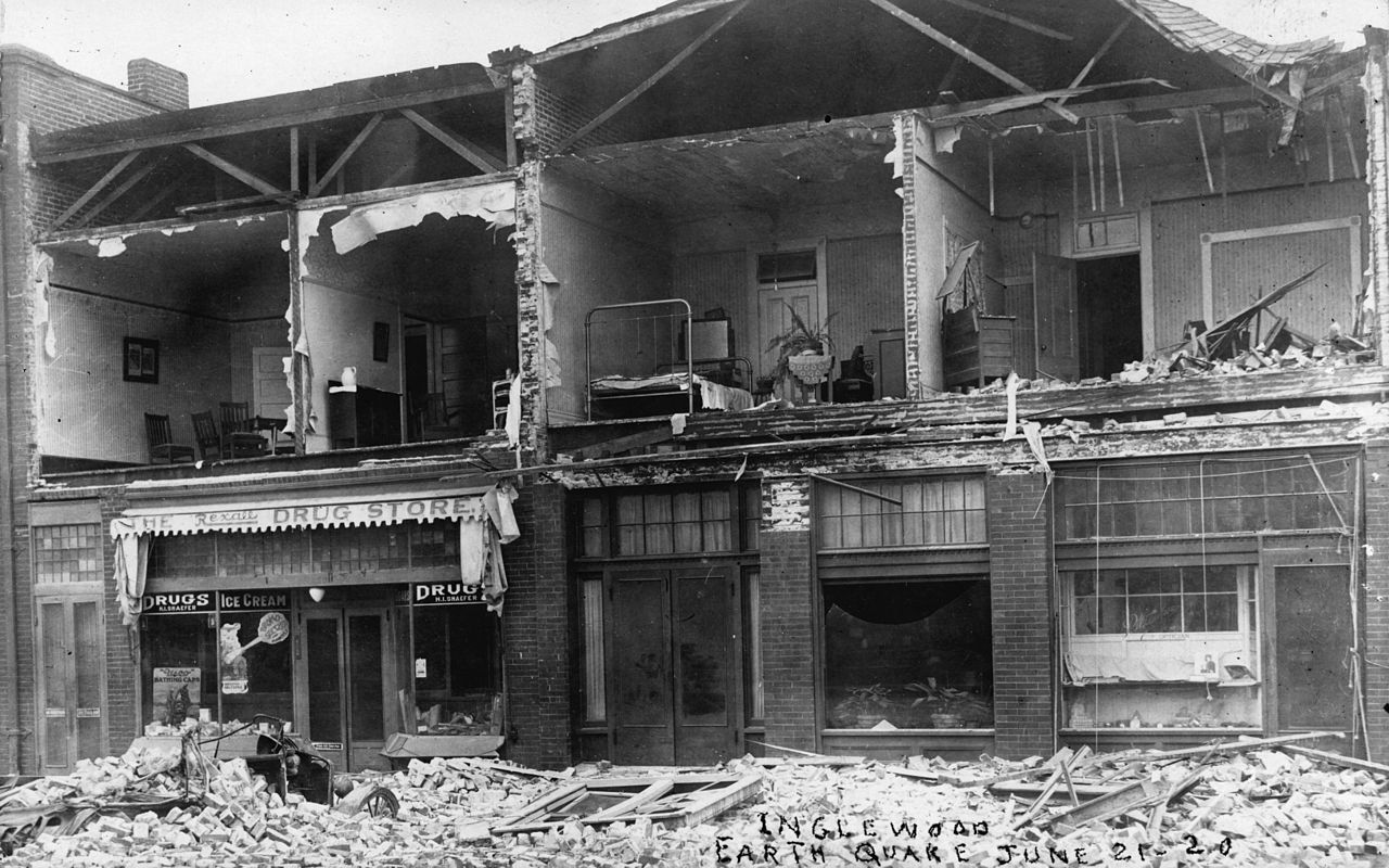 black and white photo of a row of damaged houses from an earthquake