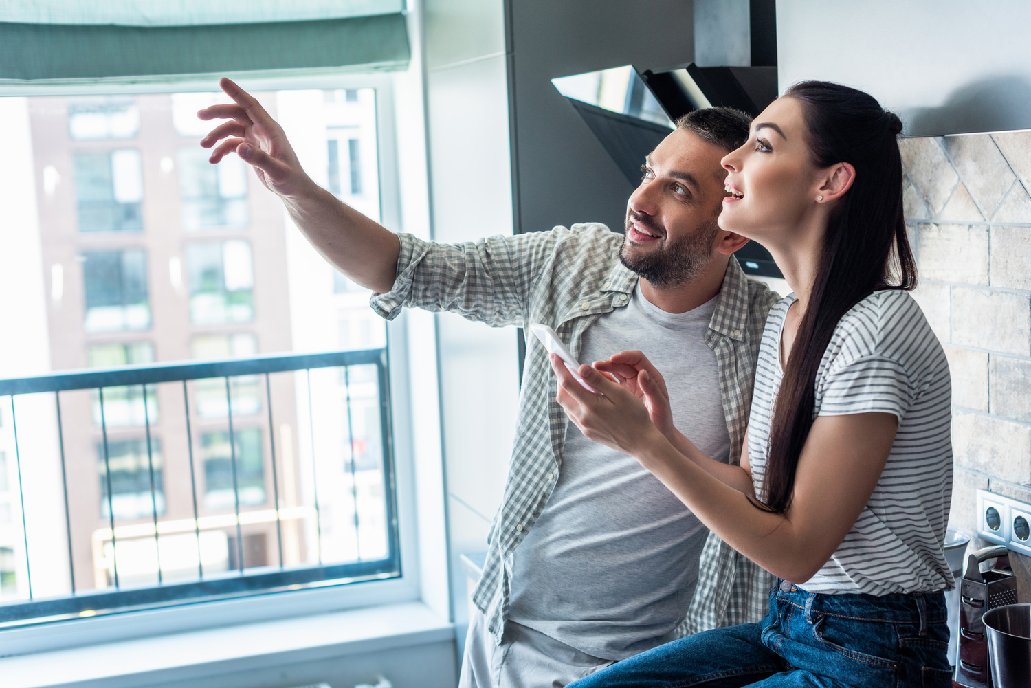 a man and a woman looking at something while pointing and using a phone