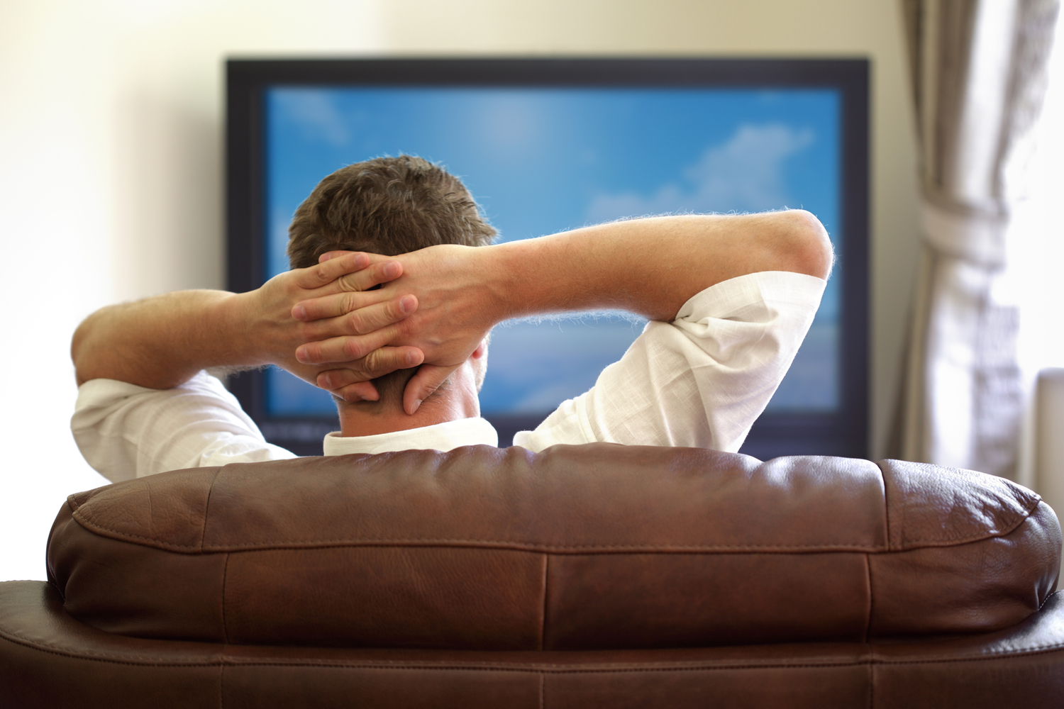 a man sitting on a leather couch watching TV