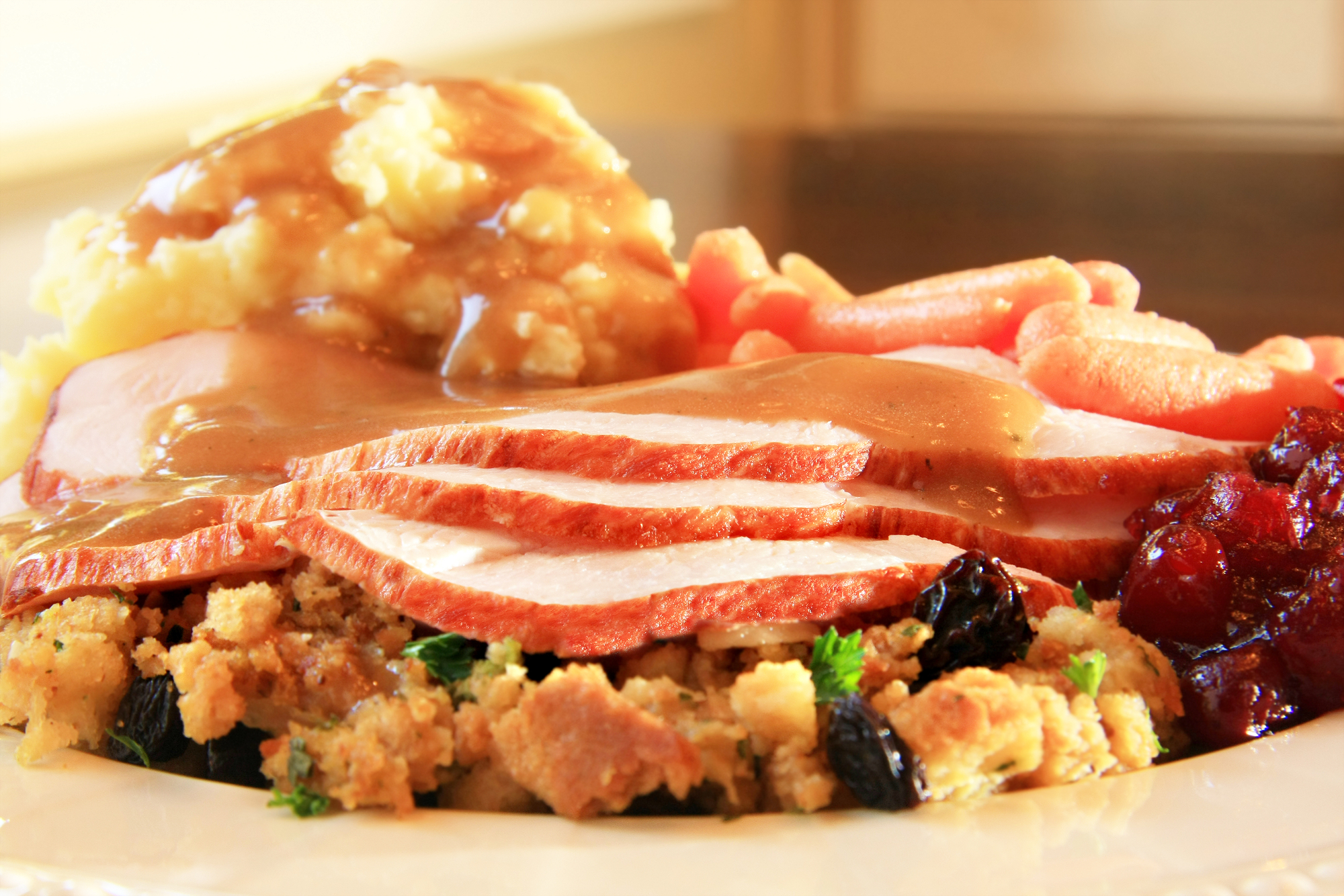 Turkey, stuffing, gravy, and mashed potatoes piled onto a plate for eating more on Thanksgiving