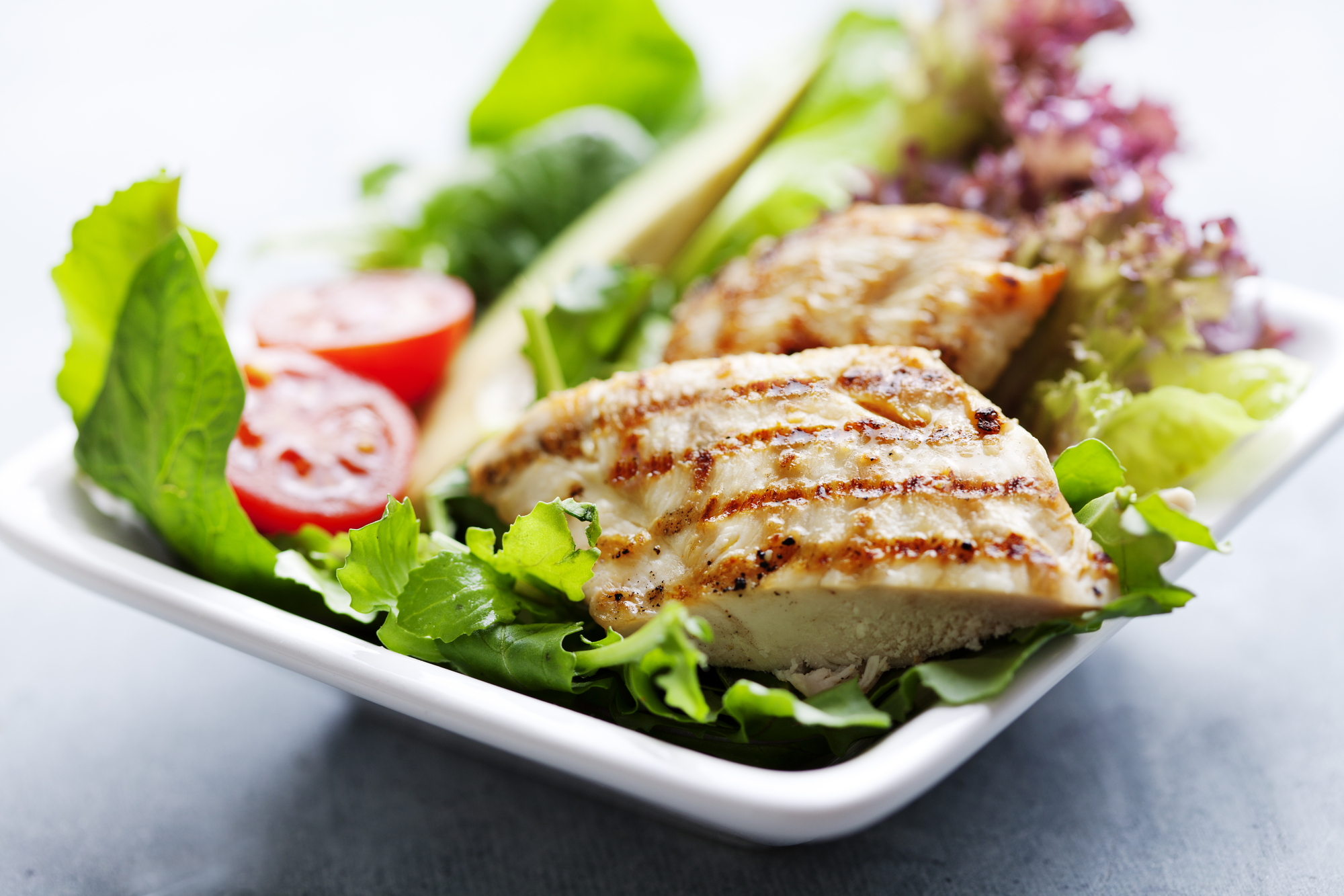 closeup of healthy salad with grilled chicken fillet, selection of lettuce, tomatoes and avocado,