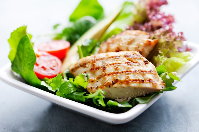 closeup of healthy salad with grilled chicken fillet, selection of lettuce, tomatoes and avocado,