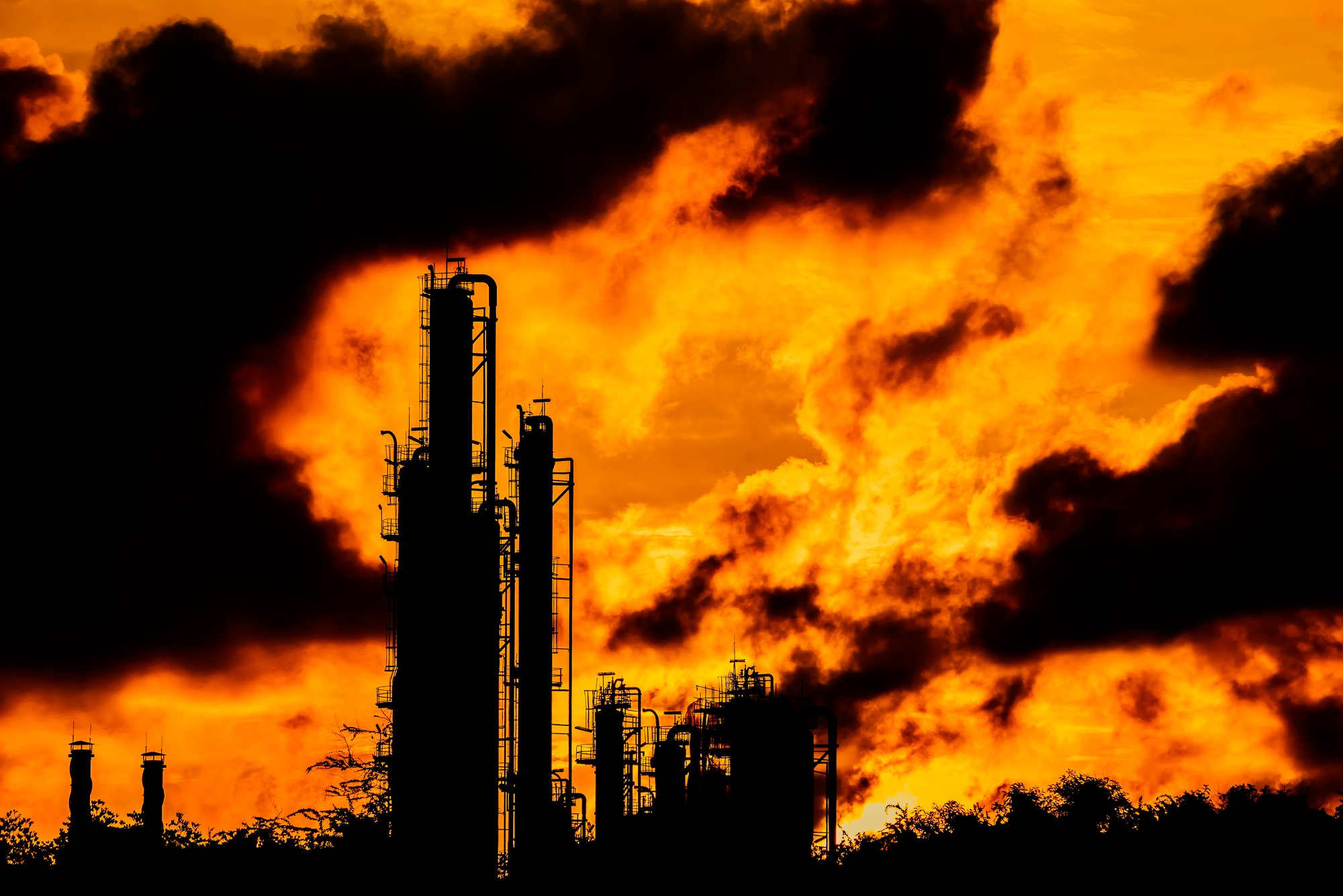 a power plant spews smoke into an orange sky