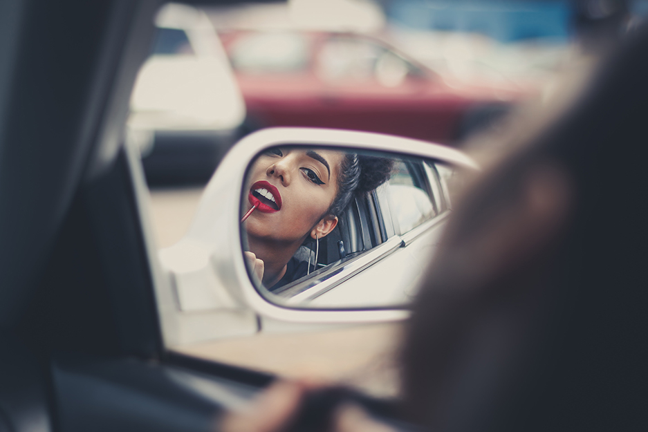 woman putting lipstick on in a car