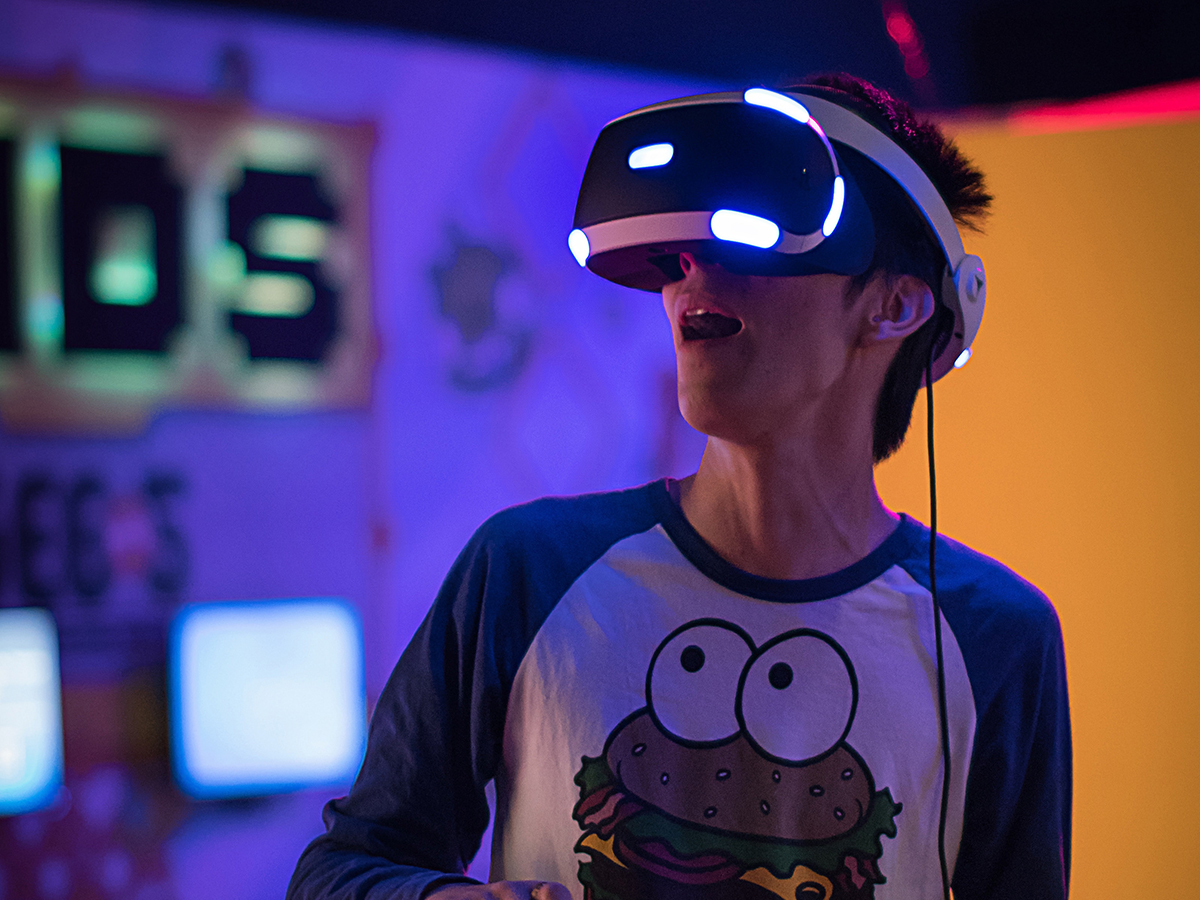 a person wearing a virtual reality (VR) headset while wearing a shirt with a sentient cheeseburger on it