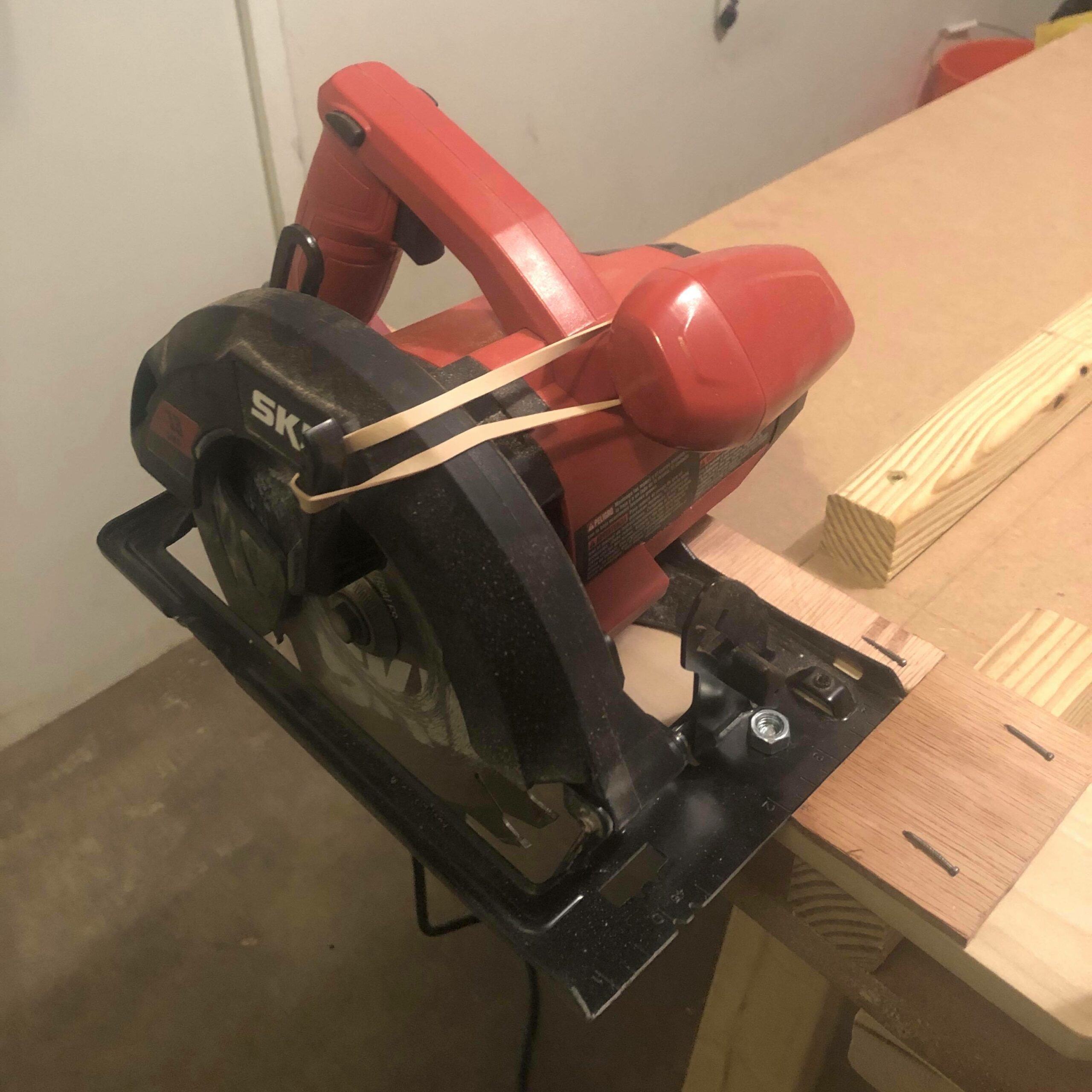 a circular saw with the blade guard locked open with a rubber band