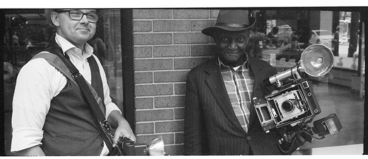 photographers dressed up against brick wall