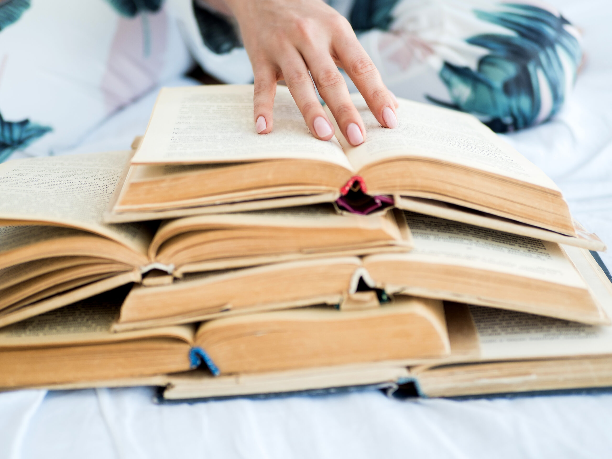 Female hand with a lot of open books.