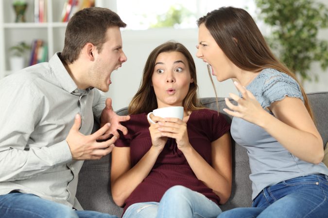 two people arguing with one person sitting awkwardly between them