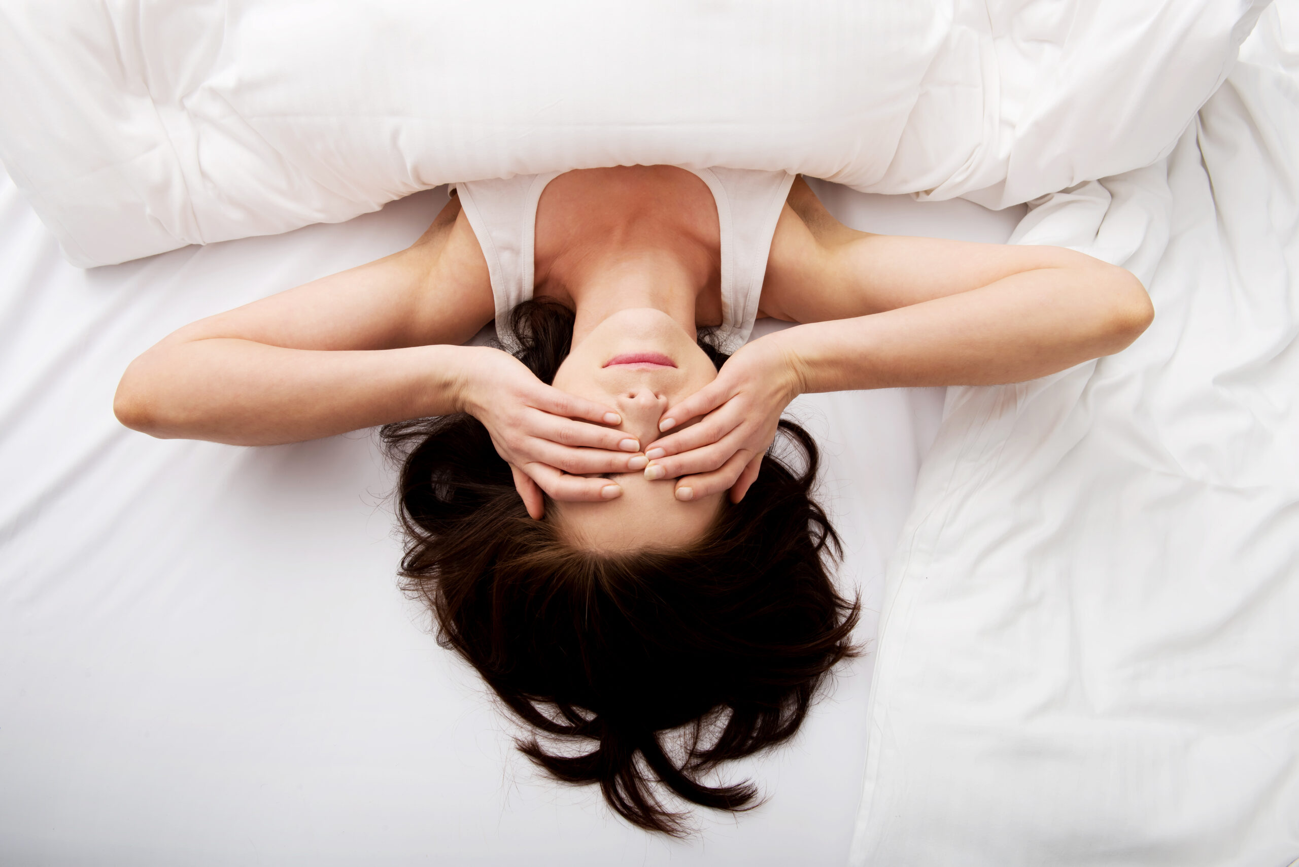 Sleepy brunette woman waking up and rubbing her eyes.