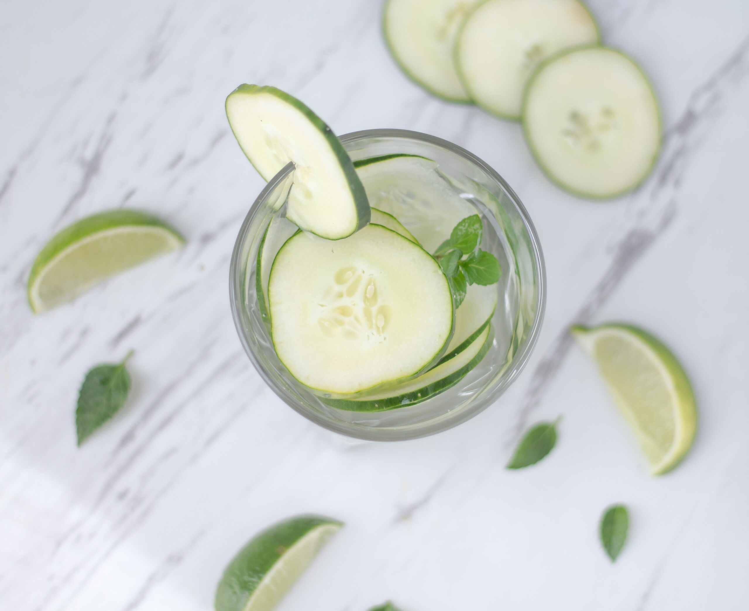 Jar of cucumber water on white marble to illustrate how to detox your body the wrong way