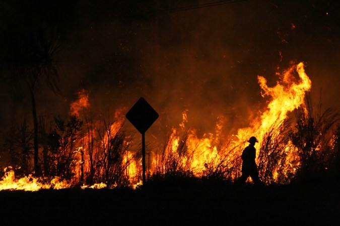 a firefighter silhouetted against a bushfire