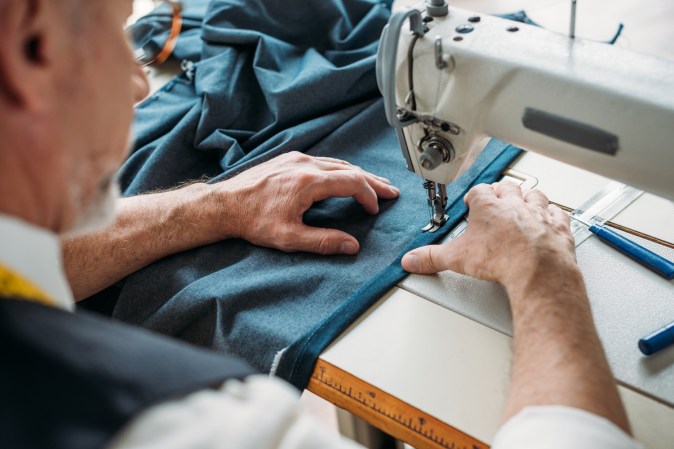 a tailor man sewing cloth on a sewing machine