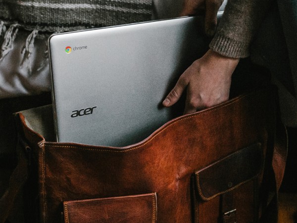 Hand in leather bag with Chromebook laptop