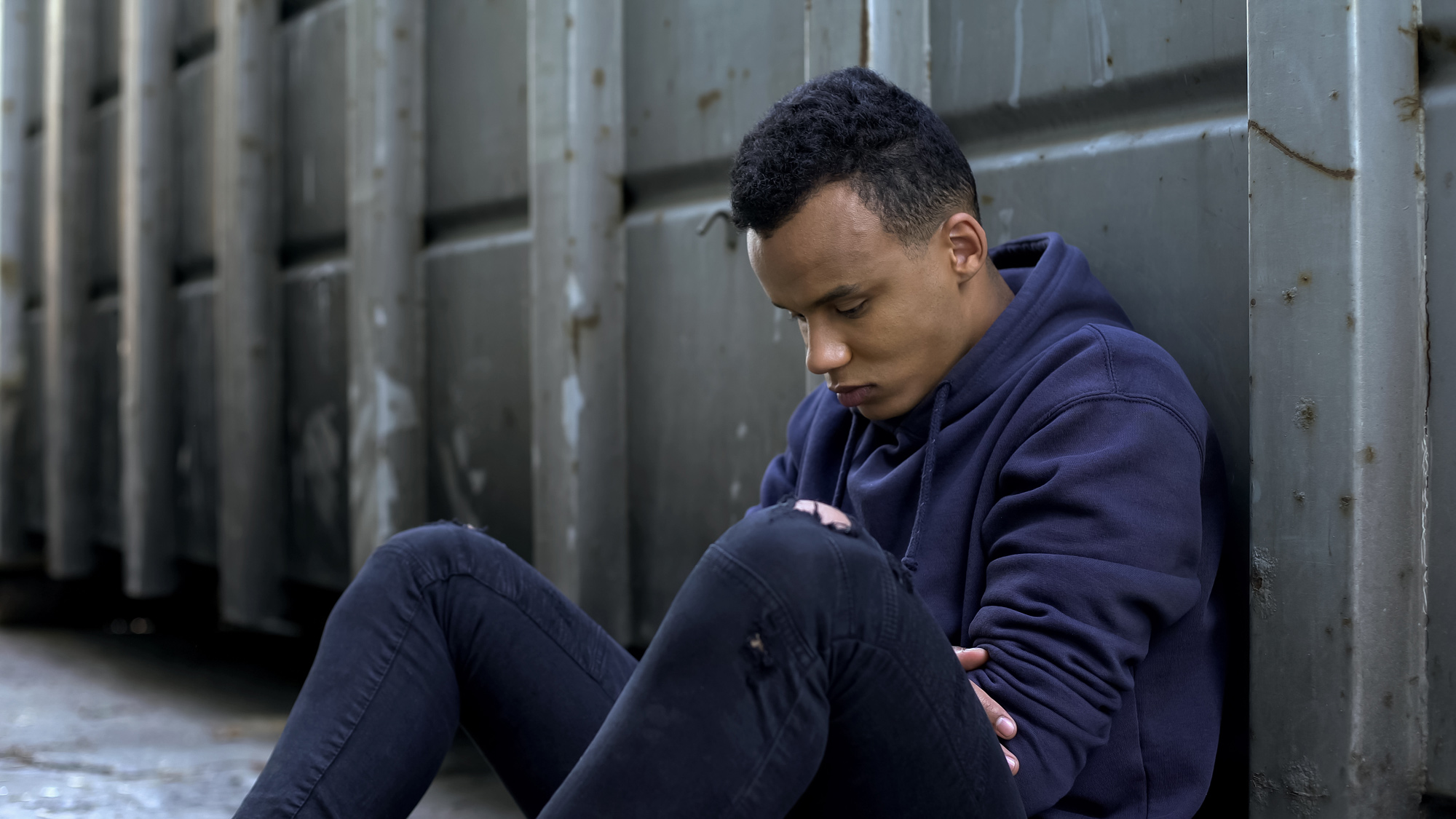 young man sitting against a wall