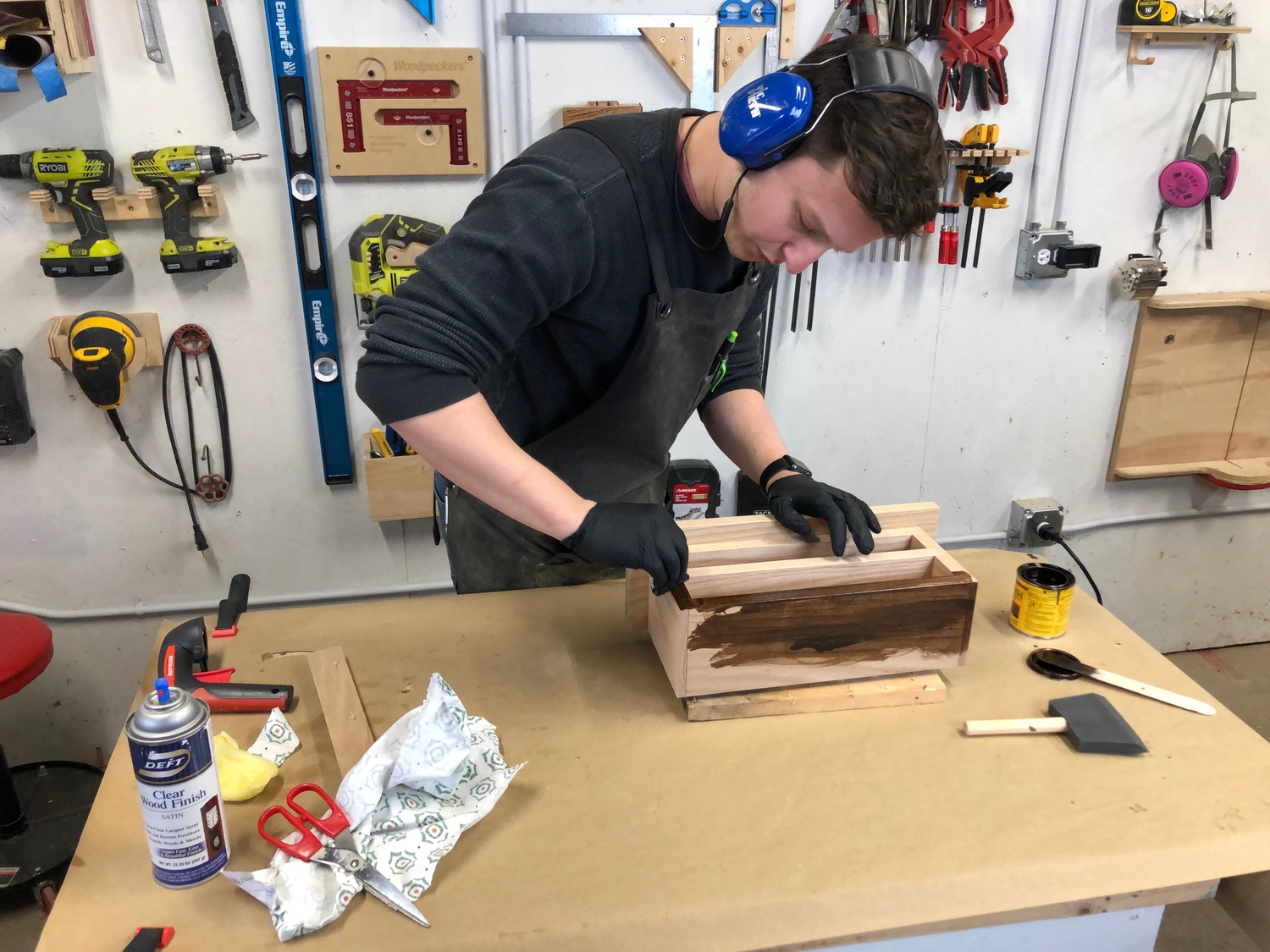 a person applying stain to a key cabinet shelf organizer