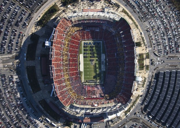 A bird's-eye view of FedExField in Maryland hosting the Army-Navy game during the day, surrounded by a parking lot full of cars.