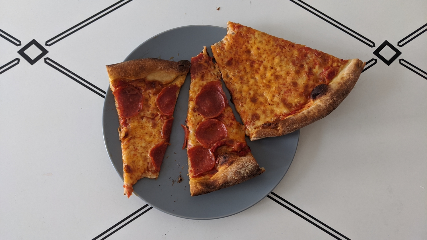 Three slices of pizza on a blue plate, after being microwaved in an experiment about how to reheat pizza.