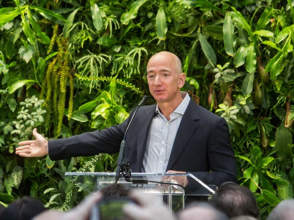 jeff bezos standing in front of a plant wall