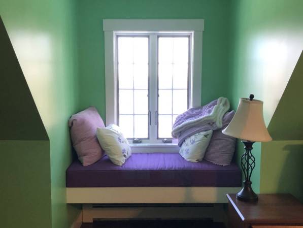 a cushioned window seat in a bedroom dormer window