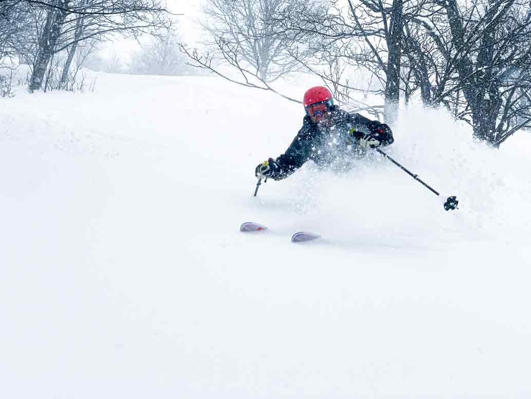 a compressed photo of a skiier skiing in snow with a red hat on during the winter