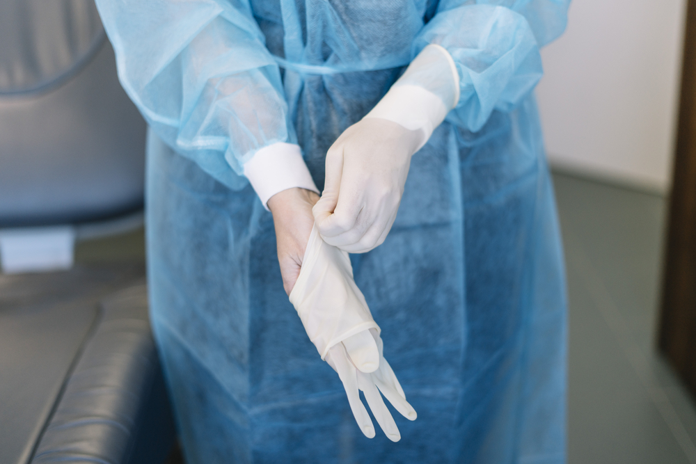 A surgeon takes their disposable gloves off.