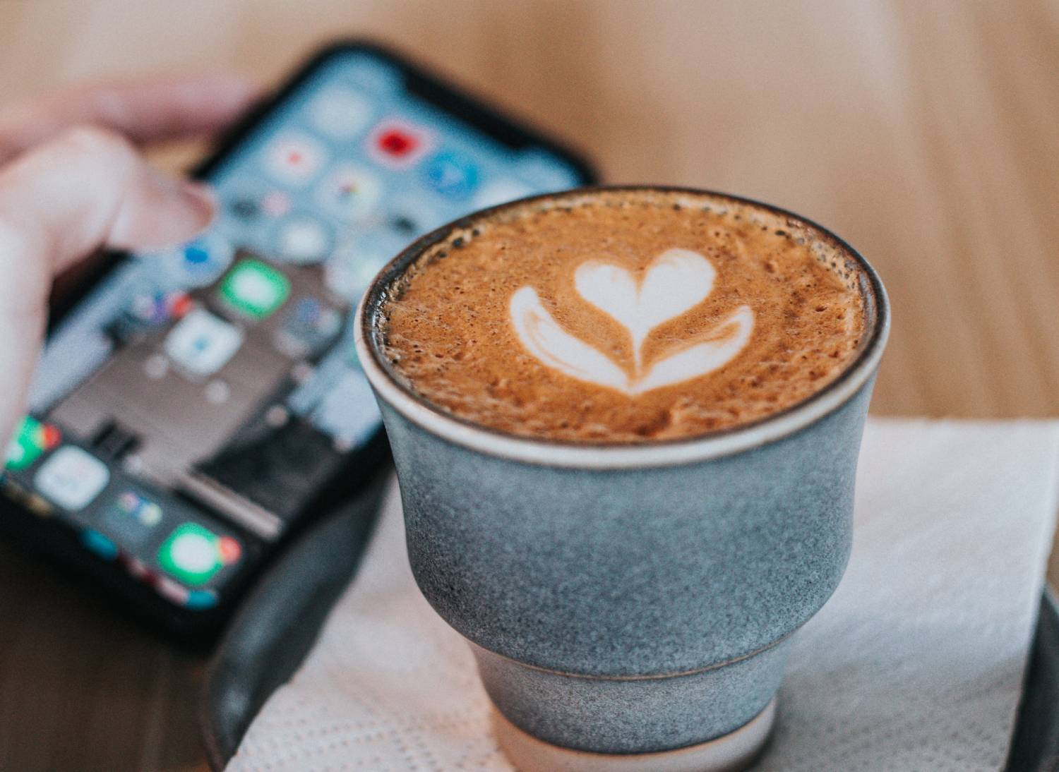 Hand holding phone in coffee shop