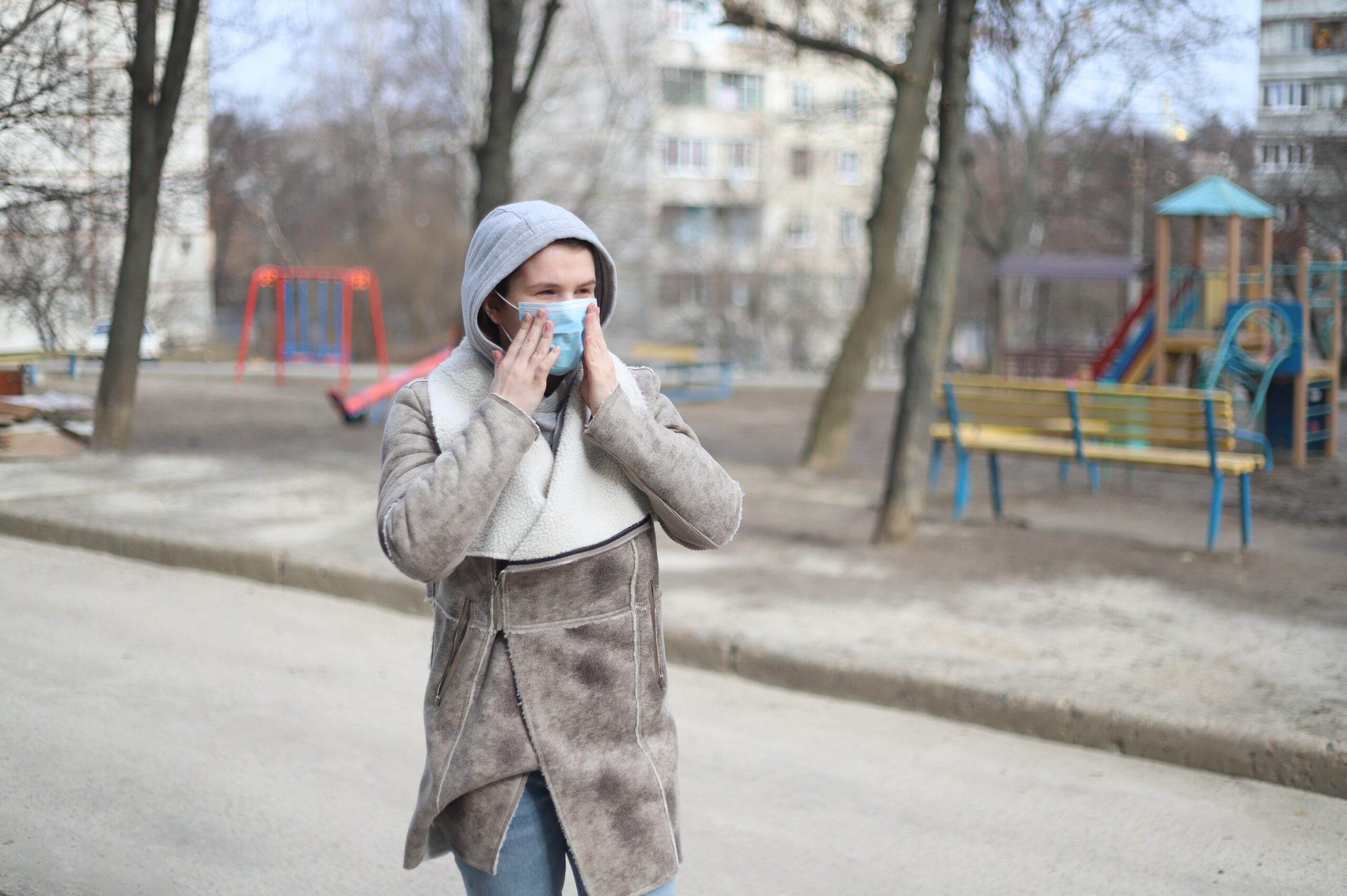 A woman in a face mask touching her face