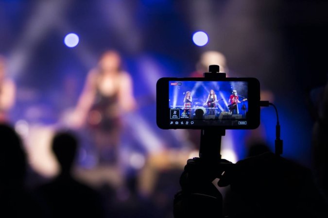 A person holding their phone up at a concert to record or live-stream the performance.