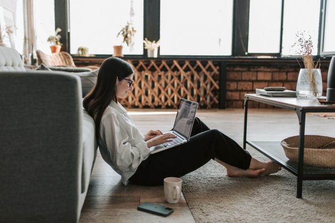 A woman working from home on the floor.