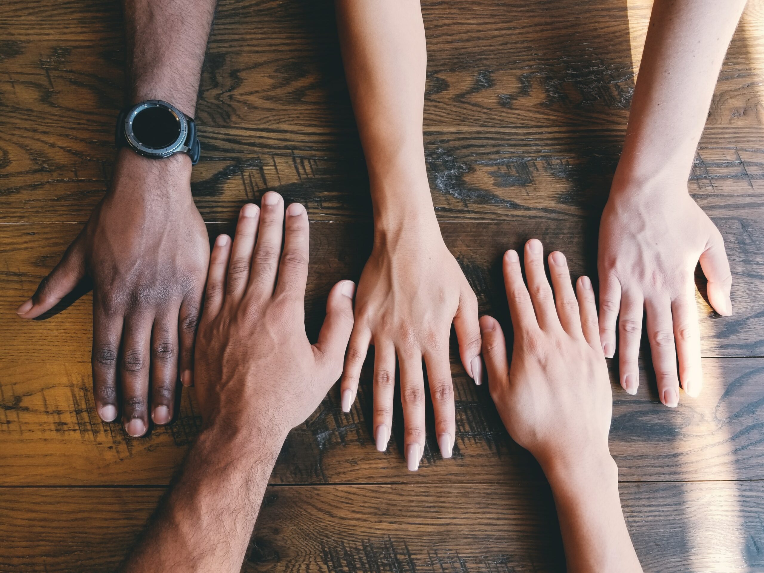 four hands with different skin colors next to each other on a table