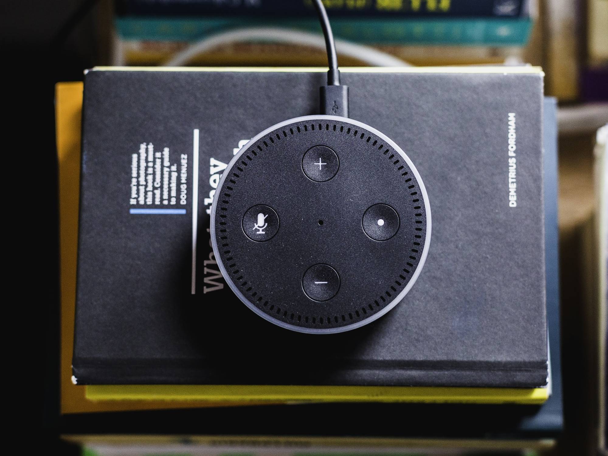 An Amazon Echo on top of a stack of books.