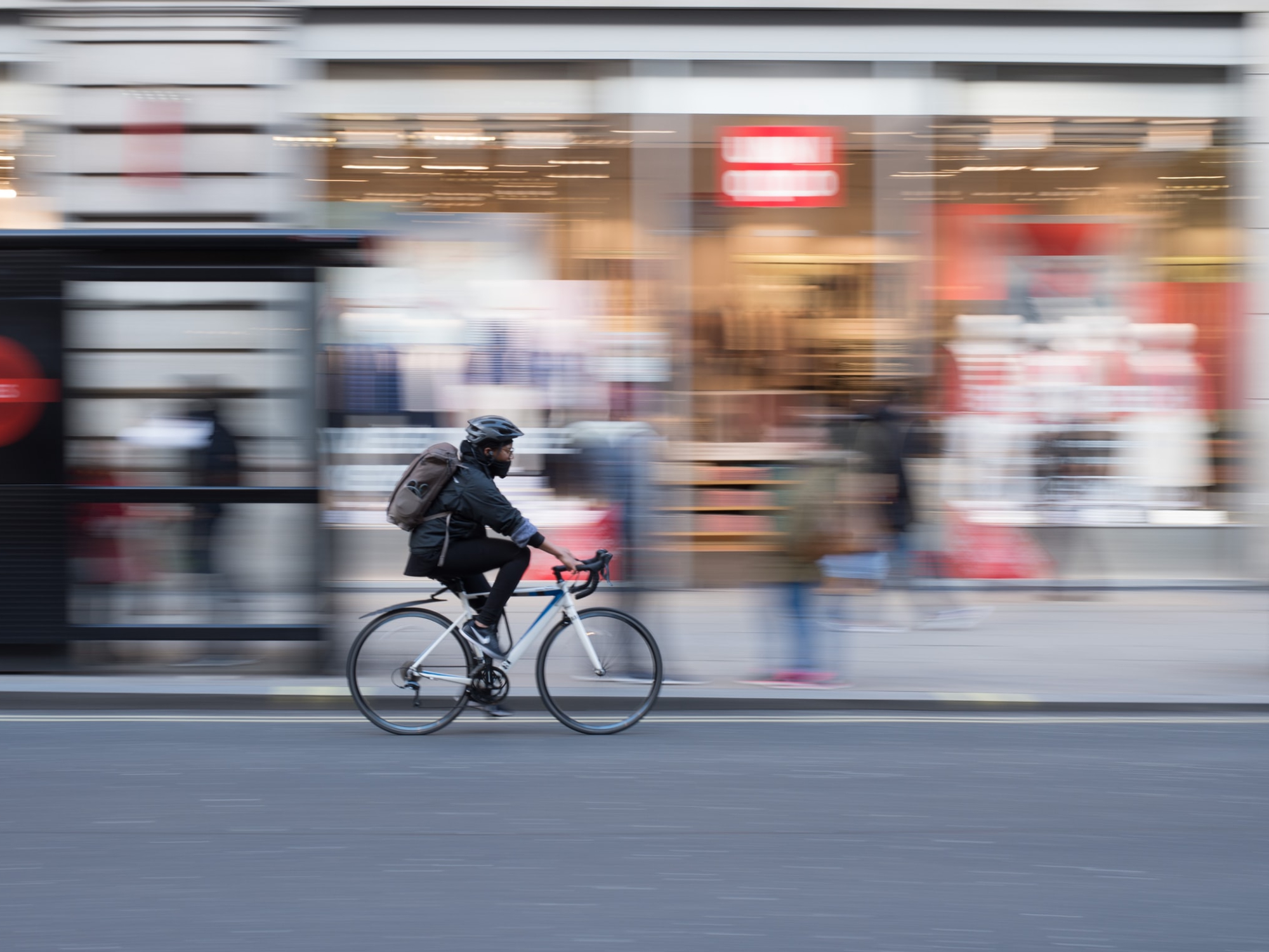 a person riding a bicycle on a street along a sidewalk