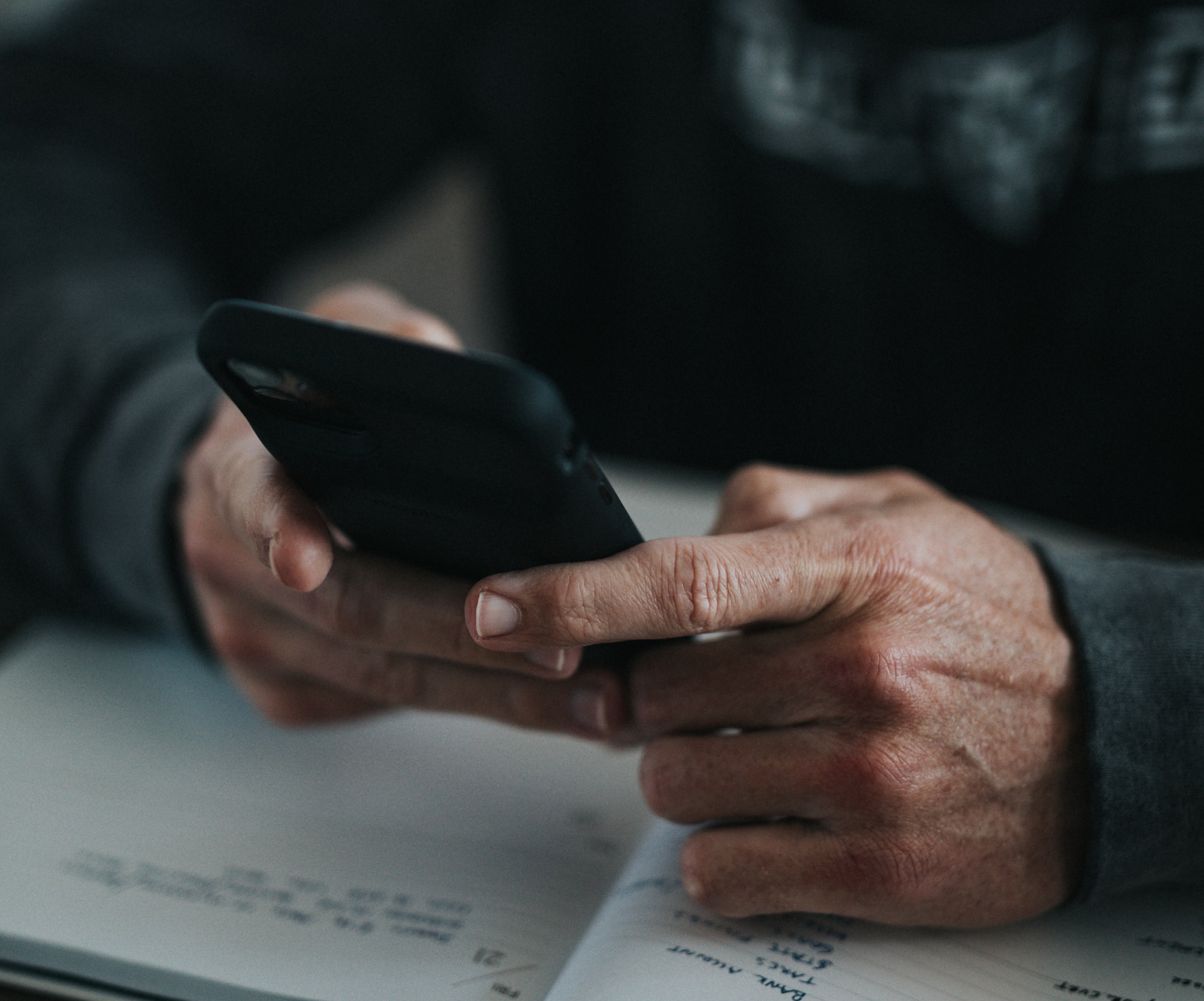 a person using their phone while also writing in a notebook