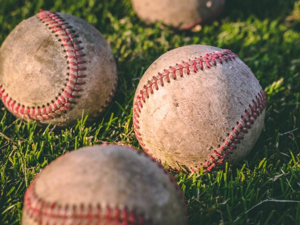 Baseballs sitting in a grassy field.