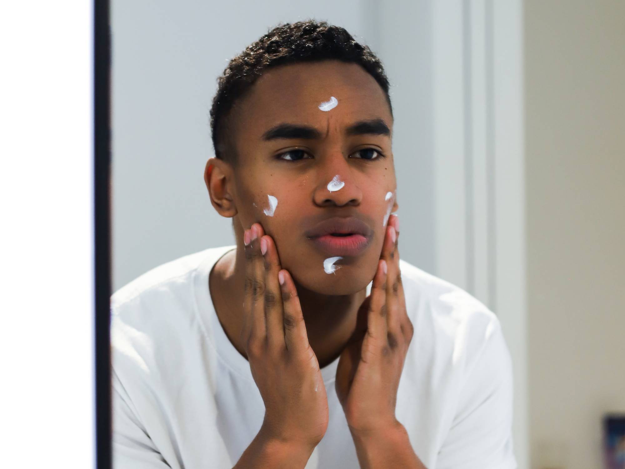 Person applying lotion in mirror