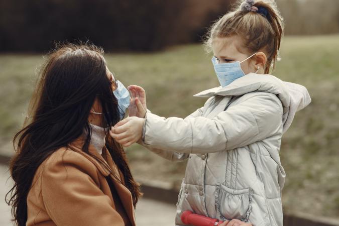 A child in a medical mask touches the face of a woman in a medical mask