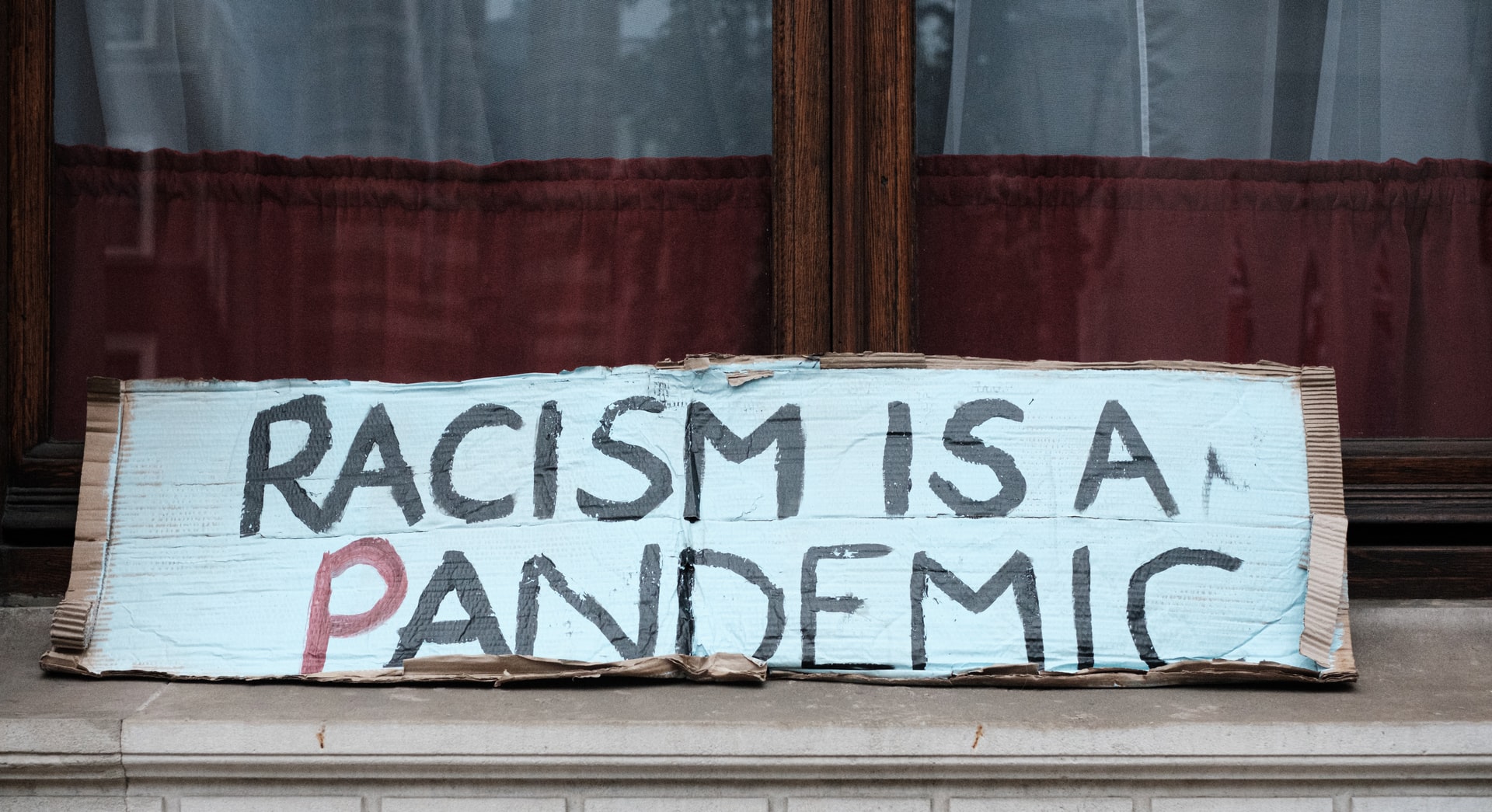 A protest sign reading "racism is a pandemic"