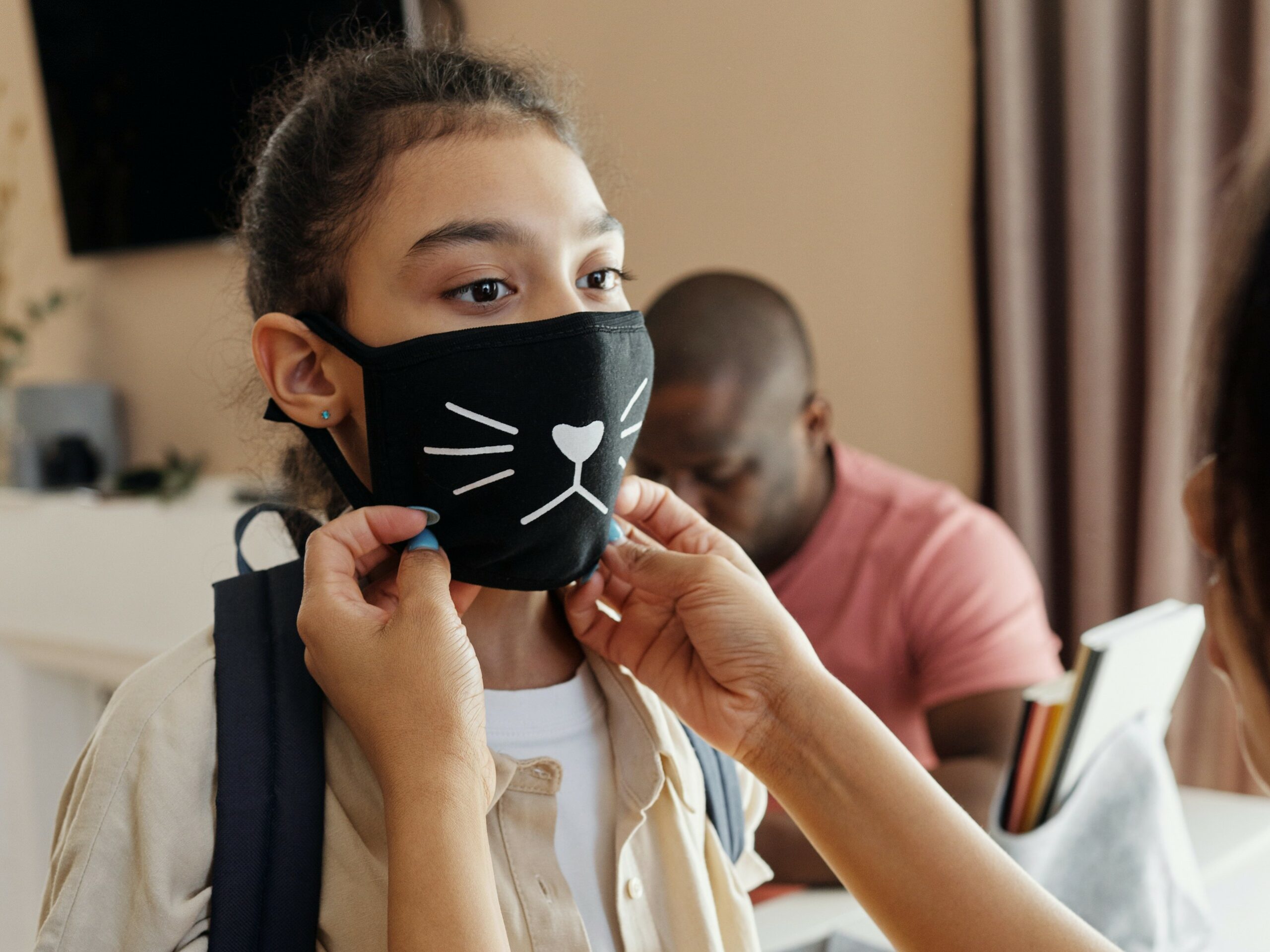 a mother putting a mask on her daughter