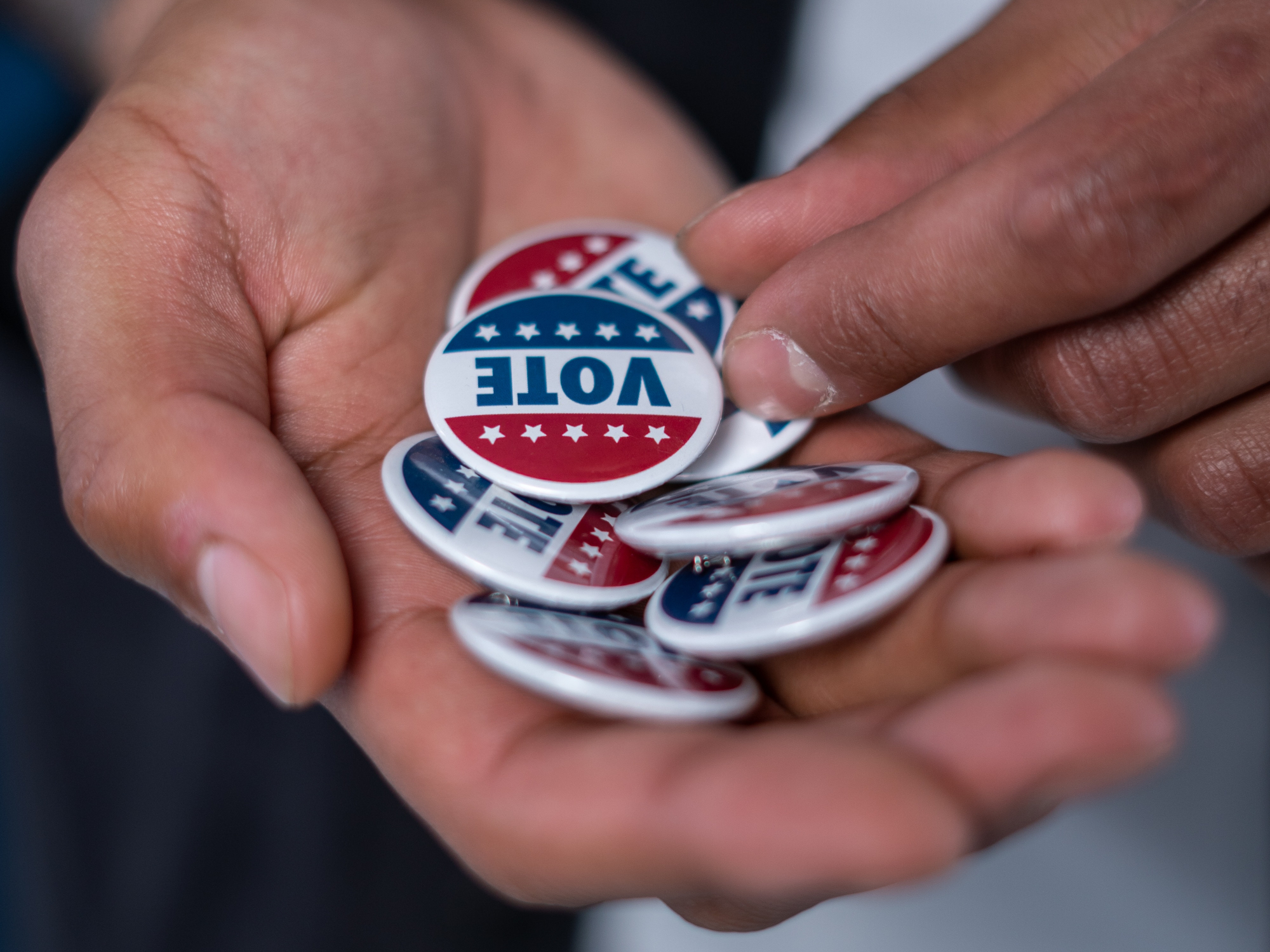 a hand holding pins that say "vote" on them