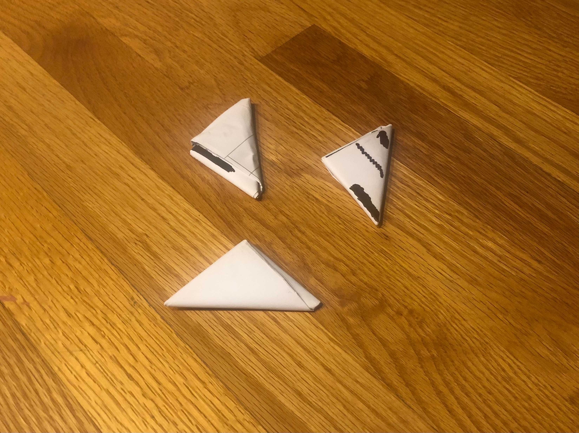 three paper footballs on some wood