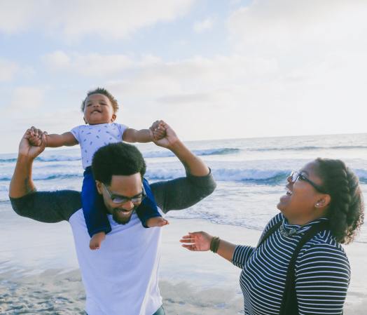 A Black family enjoying the beach with their toddler