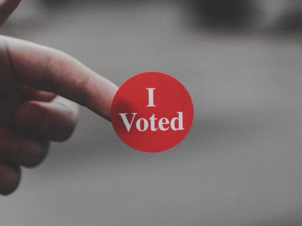 a person holding an "I Voted" sticker on their finger