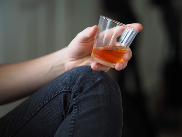 a person holding a glass of colored liquid, maybe alcohol